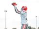 Football player in a white and red uniform catches a pass with arms raised on a field.
