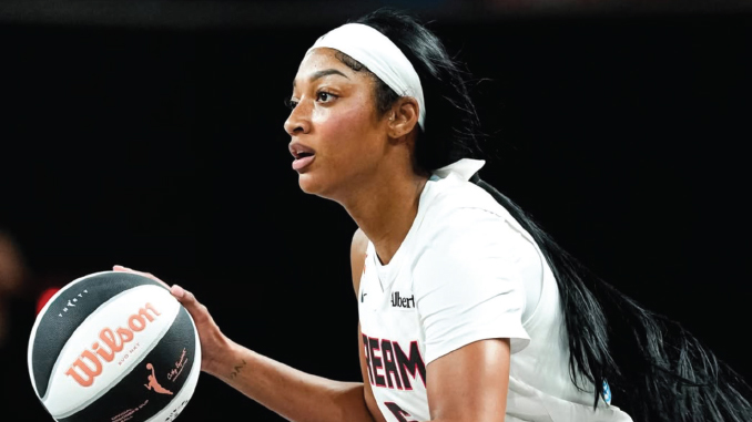 Female basketball player in a white uniform with a headband, holding a basketball and looking ahead.