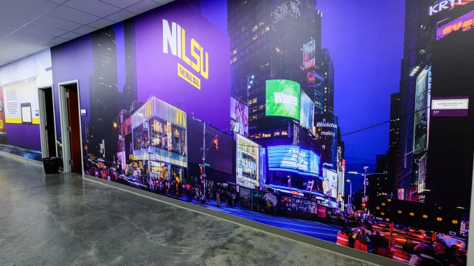 Long hallway with a wall-wide mural of a neon city at night, purple tones, bright billboards, and a McDonald's sign visible.