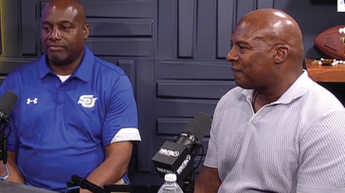 Two men sit at a podcast table with microphones; one in a blue polo, the other in a light gray polo, speaking to the camera side by side.
