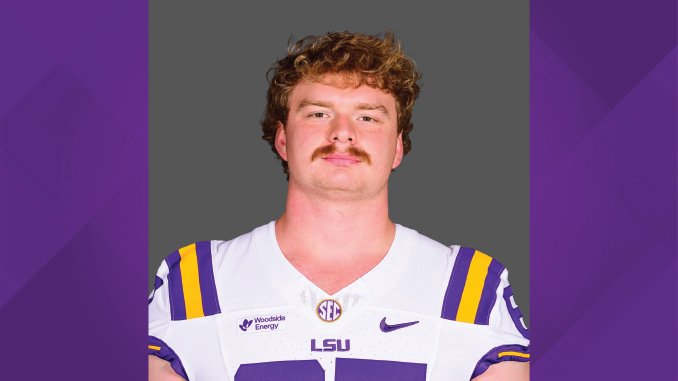 Portrait of a male LSU Tigers football player in a white jersey with purple and gold accents, facing the camera against a gray backdrop