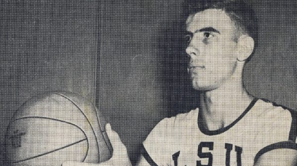 Young man in a USA basketball jersey holding a basketball and looking to the right.