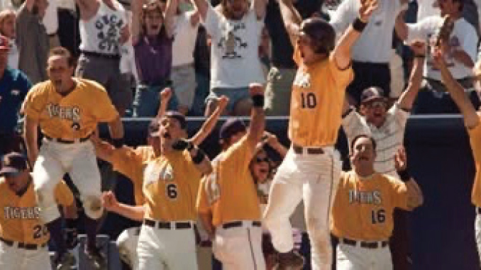Baseball players in yellow jerseys celebrate with raised arms in a stadium, fans cheering in the background.