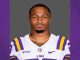 Portrait of an LSU Tigers football player wearing a purple and gold jersey, facing the camera with a neutral expression.