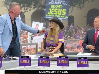 TV sports talk set with four anchors; a man in a light-blue blazer speaks to a woman in an LSU purple jersey and cowboy hat, as a suited host watches, with a large crowd and a 'Discover Jesus' sign in the background.