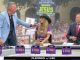 TV sports talk set with four anchors; a man in a light-blue blazer speaks to a woman in an LSU purple jersey and cowboy hat, as a suited host watches, with a large crowd and a 'Discover Jesus' sign in the background.