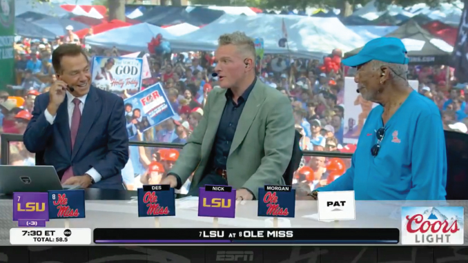 ESPN broadcast desk with three men chatting during a college football game; LSU and Ole Miss logos visible, Coors Light ad, crowded outdoor set in the background