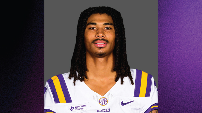 LSU football player with braided hair wearing a white jersey with purple and gold stripes, facing the camera.