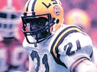 LSU football player in a white jersey and yellow helmet with number 21, during a game on the field.