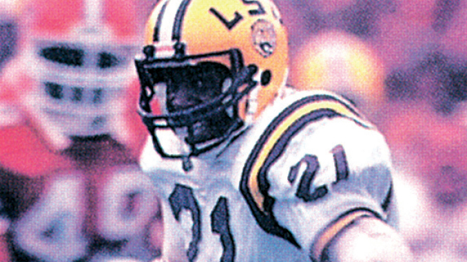 LSU football player in a white jersey and yellow helmet with number 21, during a game on the field.