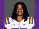 Portrait of a smiling LSU football player in a white jersey with purple and gold stripes and LSU logo, against a neutral backdrop.