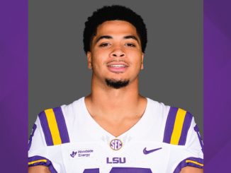Athlete in LSU football jersey facing camera, gray background.