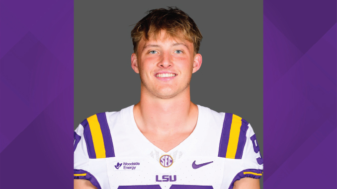 Portrait of a male LSU football player in a white jersey with purple‑and‑gold trim, against a gray backdrop.