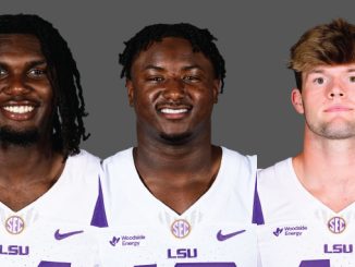 Three LSU football players smiling, wearing white jerseys with purple LSU logos, against a gray backdrop.