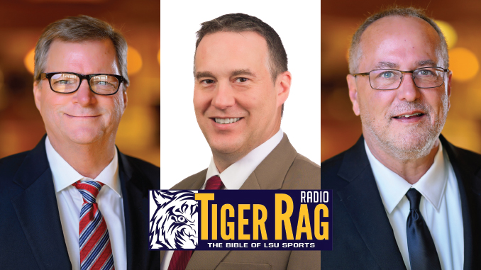 Three men in business suits posing with a Tiger Rag Radio banner for LSU sports in front of them.