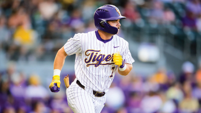 Baseball player in a white pinstripe Tigers uniform runs on the field, wearing a purple helmet and yellow batting gloves.