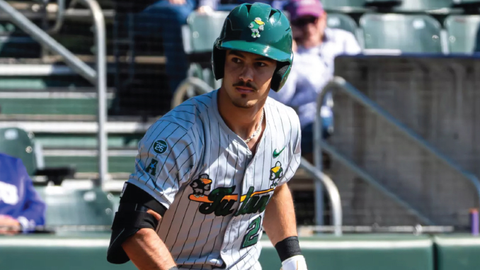 Baseball player in a pinstripe uniform and green helmet standing on the field during a game.