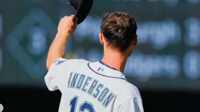 Baseball player facing away, lifting his cap in celebration on the field, jersey reads 'ANDERSON' and number 12 on the back.