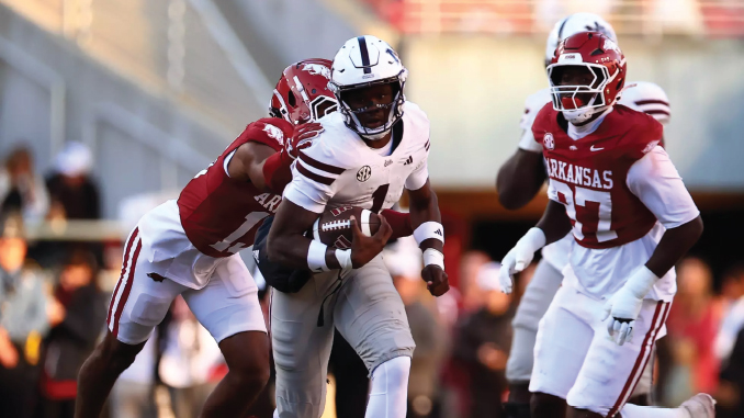Running back in white armor carries the football while two Arkansas defenders in red chase him down the field on a sunny game day.