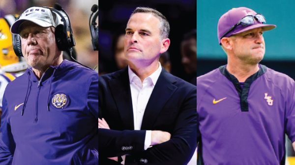 Three LSU football coaches in purple: left with headset, middle in a suit with arms crossed, right in a polo and cap.