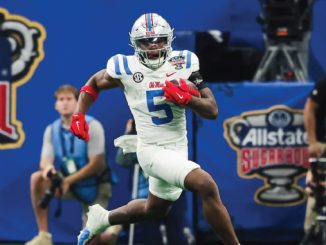 Football player in white and blue uniform sprinting with the ball during a Sugar Bowl game