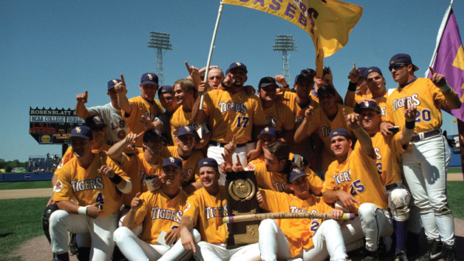 Group of Tigers baseball players in gold jerseys pose with the championship trophy on the field, celebrating a win.