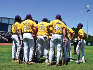 Huddle of baseball players in yellow uniforms on the field, backs visible with names and numbers 25, 33, 44, facing inward for a team discussion