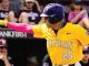Baseball player in a yellow Tigers jersey with number 25, helmet on, pointing with his left arm during a game.