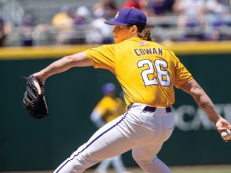 Baseball pitcher in a yellow jersey with 'COWAN' and number 26 throws a pitch on the mound, glove raised left, ball in right hand