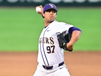 Baseball pitcher in a white and purple uniform, number 97, mid-pitch on the mound with glove ready and ball released.