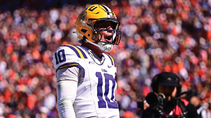 LSU football player in white jersey number 10 with a yellow helmet on the field, shouting during a game
