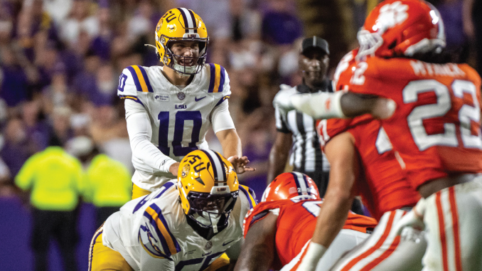 LSU football: quarterback #10 in white drops back to pass amid red-clad defense and a blocking teammate nearby.