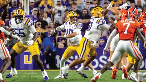 LSU quarterback (number 10) drops back to pass while teammates block and defenders rush.