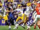 LSU quarterback (number 10) drops back to pass while teammates block and defenders rush.