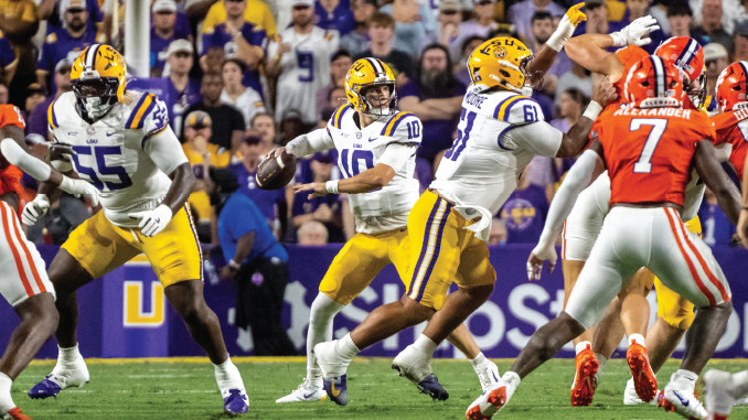 LSU quarterback (number 10) drops back to pass while teammates block and defenders rush.