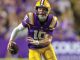 LSU Tigers quarterback wearing purple and gold, number 10, running with the football during a game.