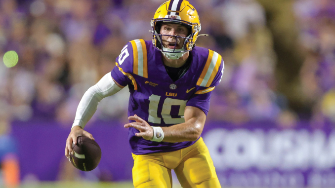 LSU Tigers quarterback wearing purple and gold, number 10, running with the football during a game.