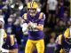 LSU quarterback in purple and gold prepares to throw, during a game under bright stadium lights.