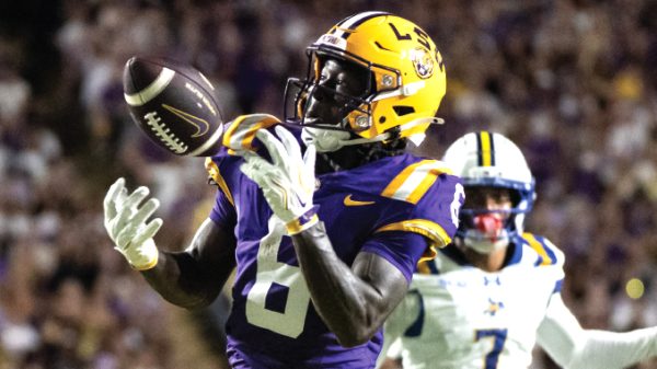 LSU Tigers football player in purple and gold catching a pass during a game, ball secured in midair.