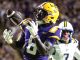 LSU Tigers football player in purple and gold catching a pass during a game, ball secured in midair.