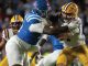 Ole Miss running back stiff-arms LSU defender during a college football game on a night stadium field