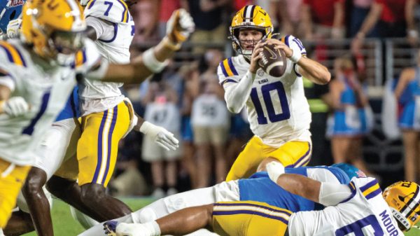 LSU quarterback #10 throwing a pass while defenders close in during a football game.