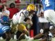 LSU running back carries the football while an Ole Miss defender tackles him during a college football game.