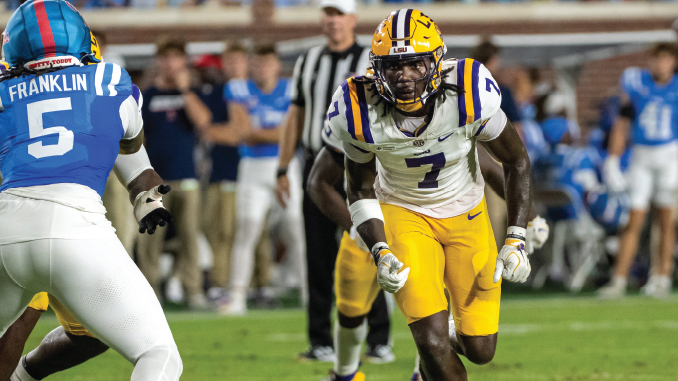 LSU #7 in white and gold races toward a defender, Franklin #5 in blue defends on a college football field.