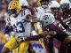 LSU running back #13 carries the ball, dodging Texas A&M defenders during a tight college football play.