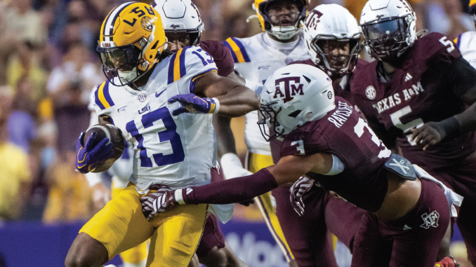 LSU running back #13 carries the ball, dodging Texas A&M defenders during a tight college football play.