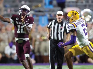 Texas A&M quarterback wearing maroon jersey throws a pass as LSU defender in white and yellow chases him, with a referee in the background.