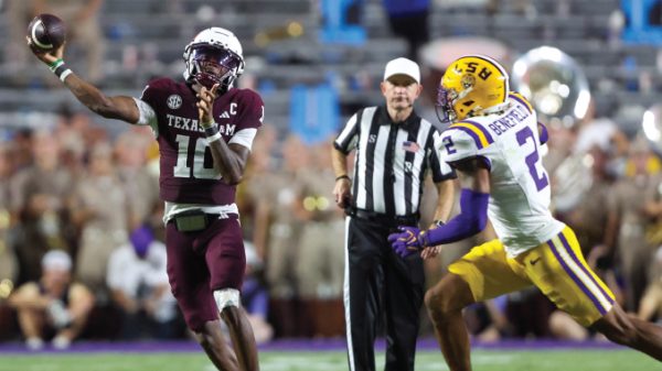 Texas A&M quarterback wearing maroon jersey throws a pass as LSU defender in white and yellow chases him, with a referee in the background.