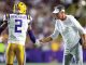 LSU Tigers player Benefield (#2) in white jersey shakes hands with a coach on the sideline during a game.