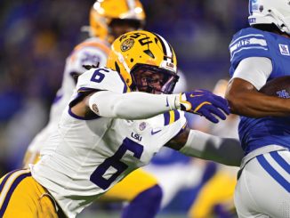 LSU defender in white jersey (#6) reaches to tackle a blue-clad opponent holding the football.